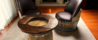 Barrel lounge chairs and a round Wine Barrel table by a lit fireplace